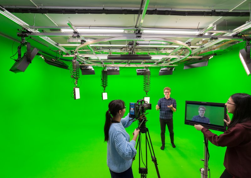 Students shooting a studio with a green screen backdrop.