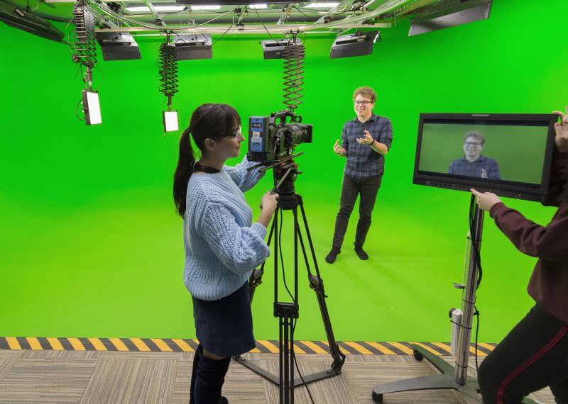 Falmouth students working camera and viewing a screen in a green studio.