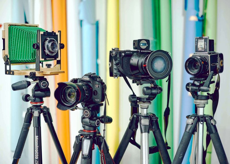 Four cameras on tripods in front of a colourful background