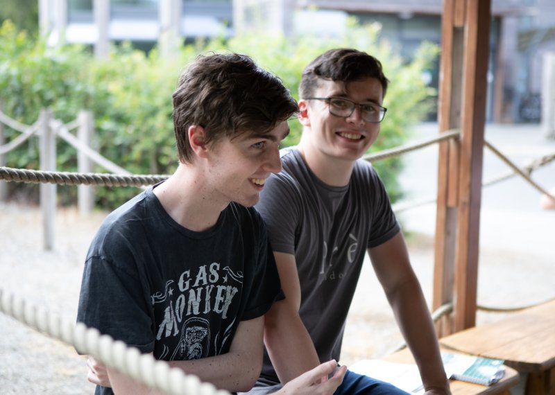 Two male students seated outside and smiling