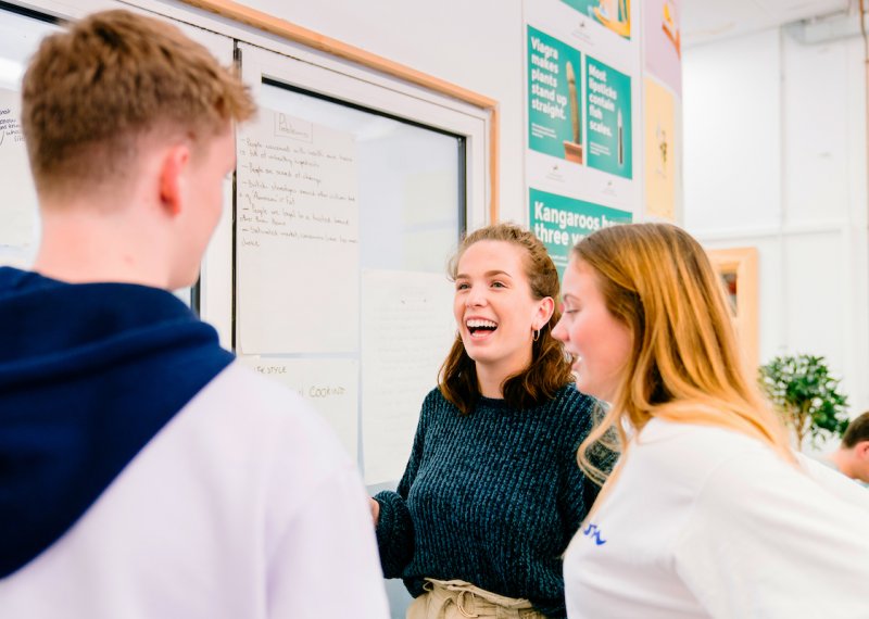 Three creative advertising students talking while standing
