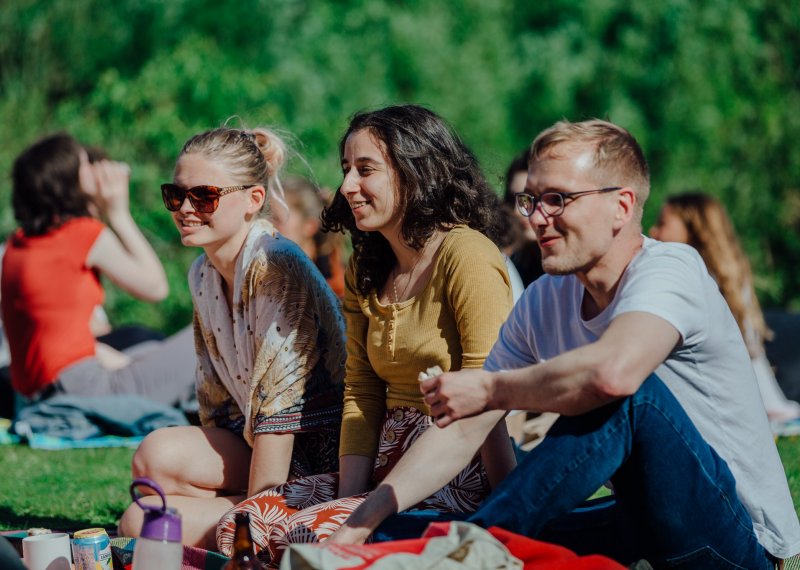 Falmouth international students sitting on the grass in the sunshine.