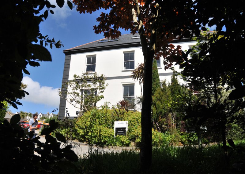 Exterior of period building on Falmouth campus surrounded by trees and greenery.