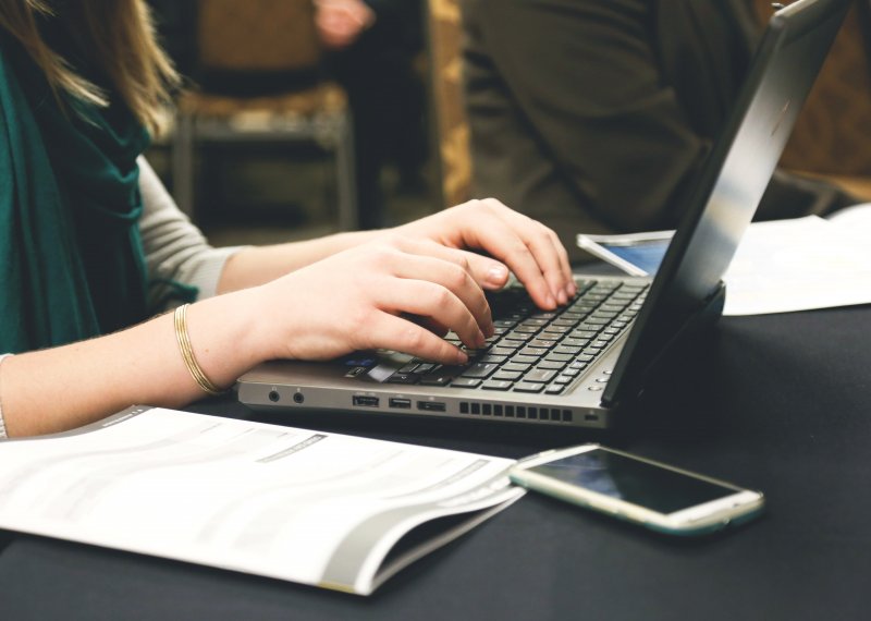 Woman studying at laptop with books and journals