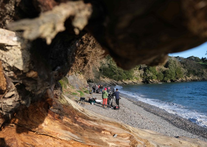 A group of students can be seen through the gap in a rock