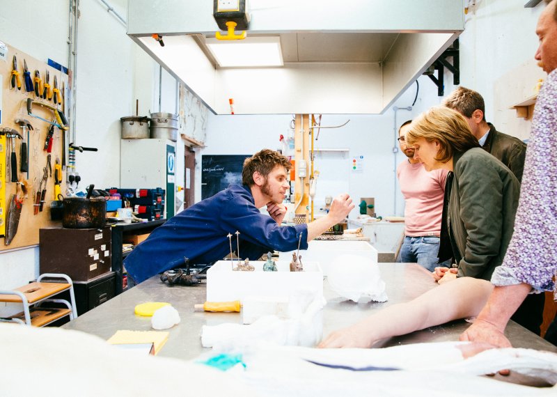 Falmouth University technician showing small object to three people in a workshop