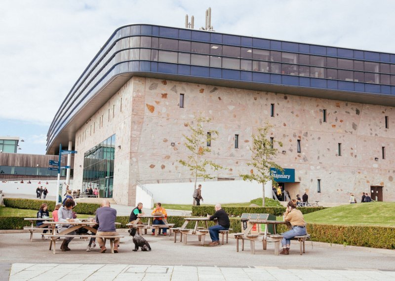 People and benches outside the Stannary buidling on Penryn campus.