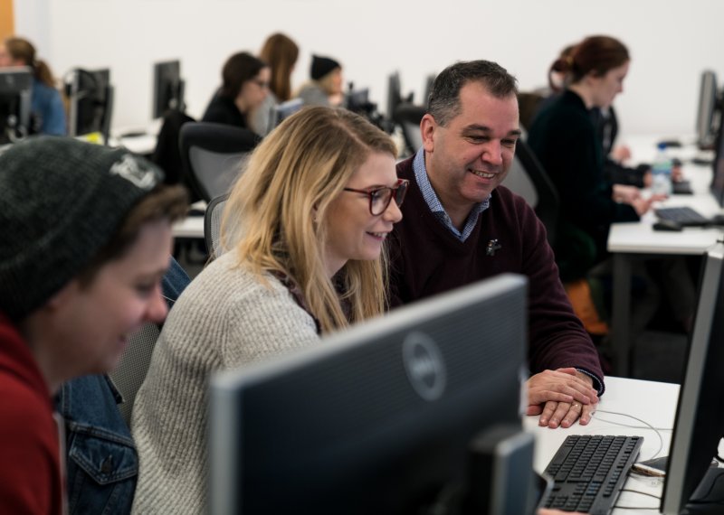 Student and lecturer working in room full of computers.