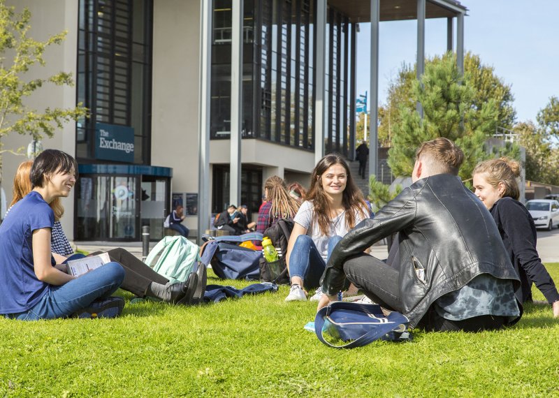 Students sitting on grass at Penryn campus.