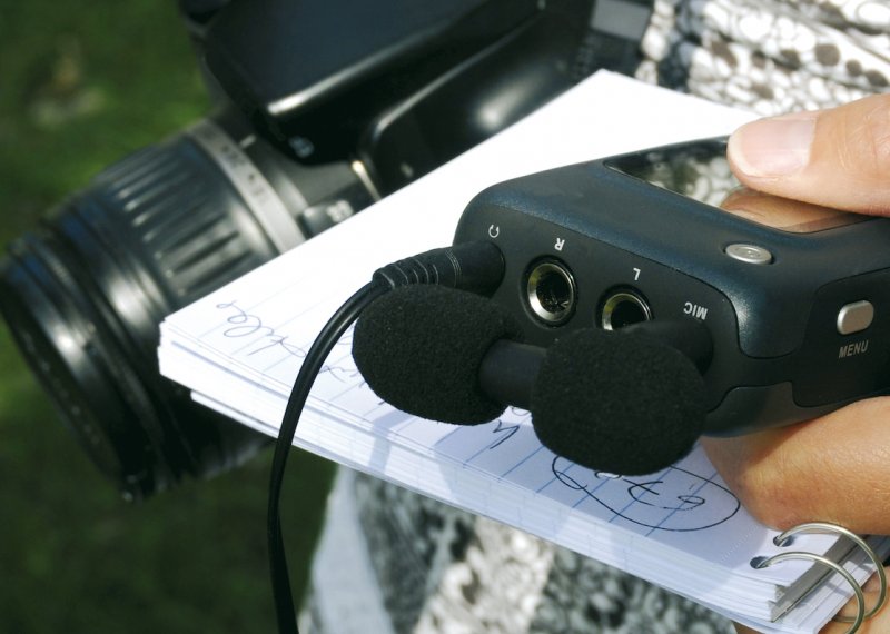 Close up of dictaphone, notepad and SLR camera