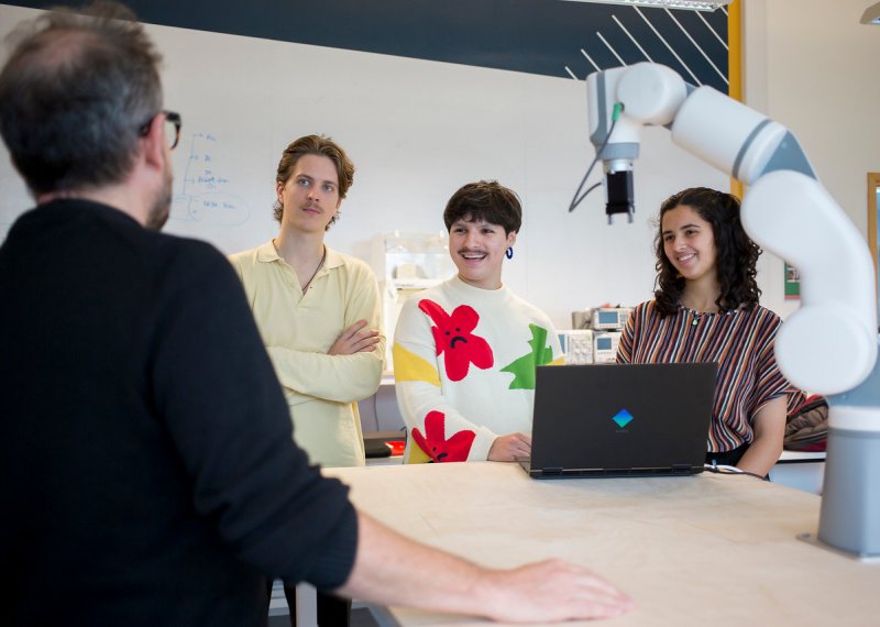 Falmouth University students listening to a lecturer around a table