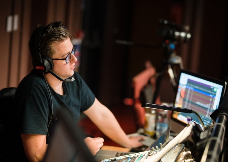 Male student wearing a headset in front of a sound desk