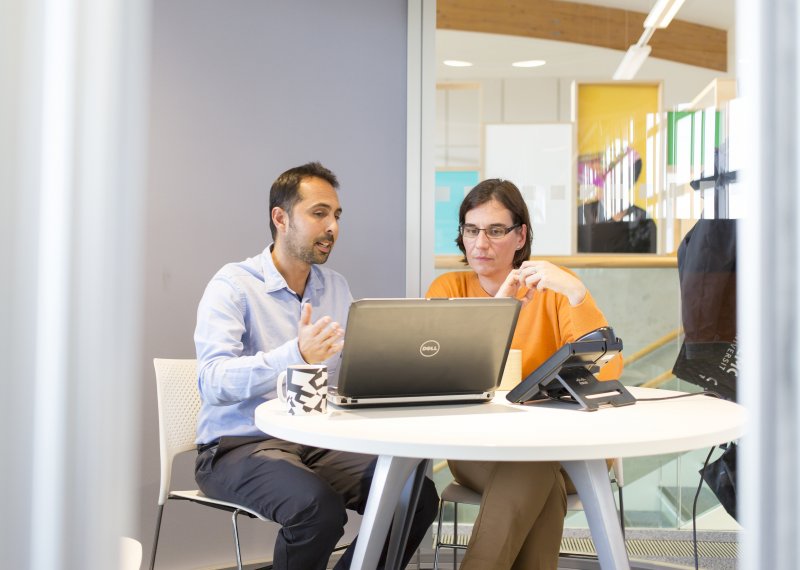 Staff looking at a laptop and gesturing with hand.