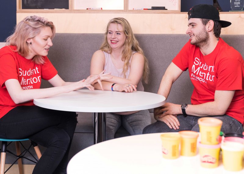 Students mentors chatting around table.