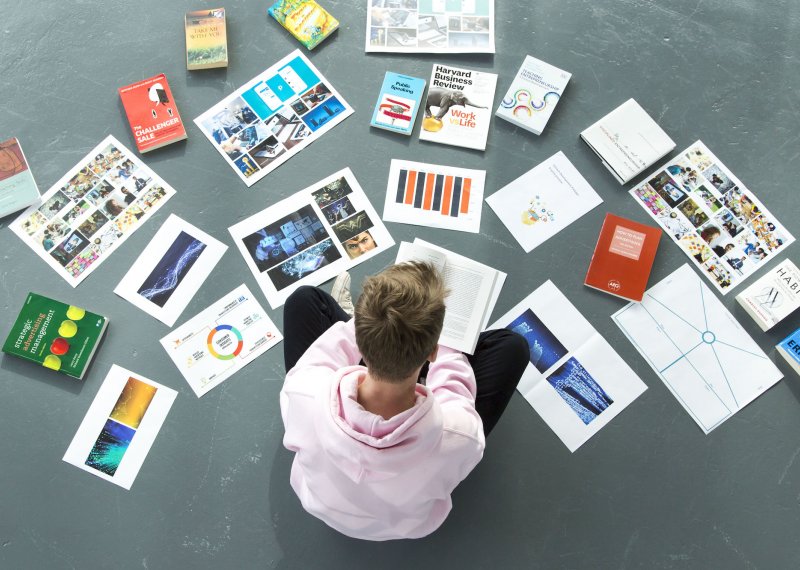 A Falmouth University student sat on the floor surrounded by papers and books