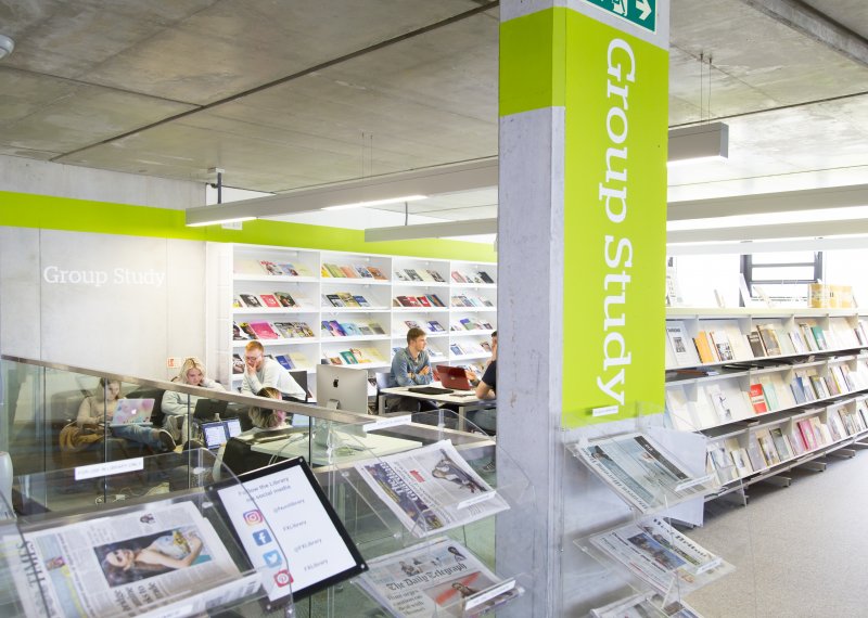 Library interior with 'group study' written on large pillar and students reading