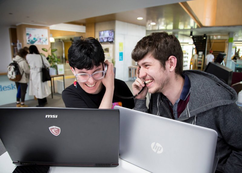 Falmouth University students listening and laughing on their headphones