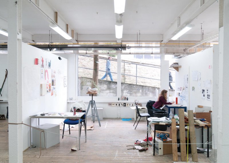 Art student working in studio with large window on Falmouth campus and person walking past and looking in.