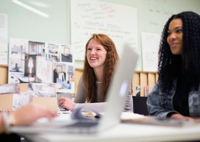 Smiling fashion marketing students working together around a desk.