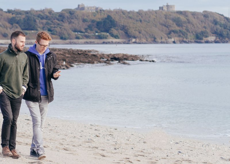 Living support students walking and chatting on beach.