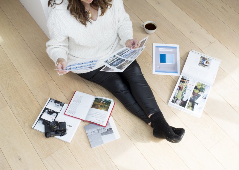 An online photography student sat on the floor with their work