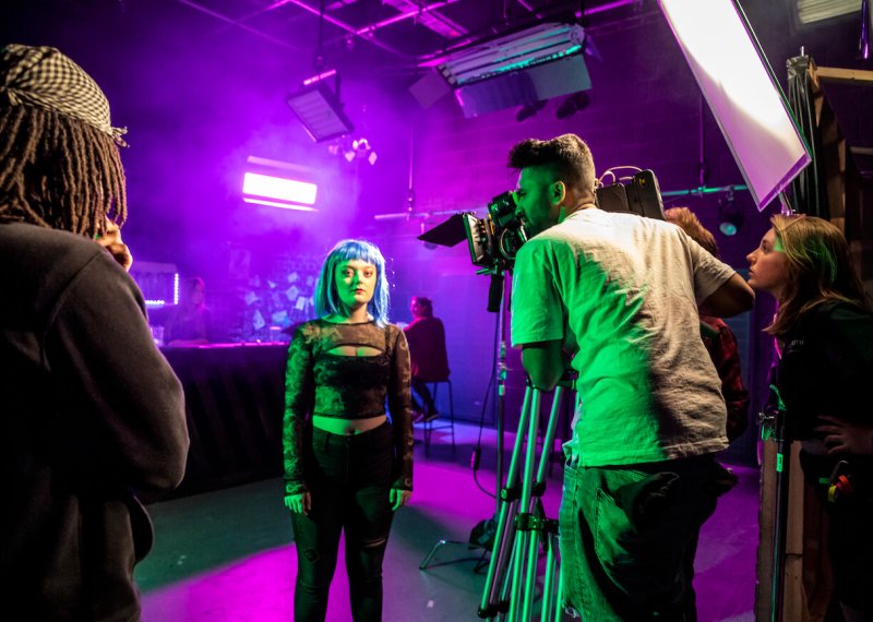 Falmouth University students in a purple lit film studio with camera