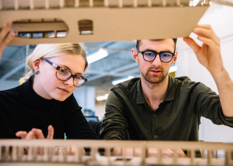 Interior design students looking at cardboard model