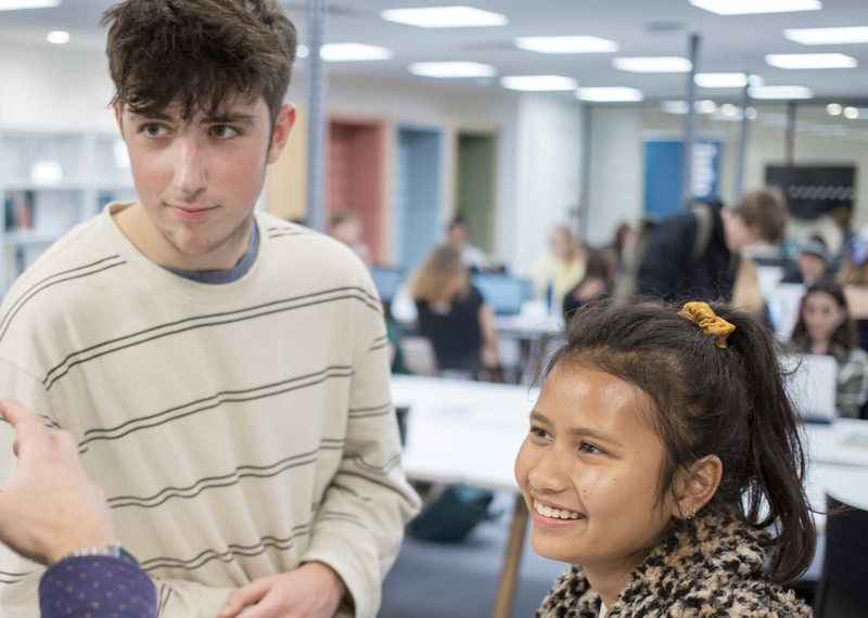 Two students speaking a staff member in The Compass