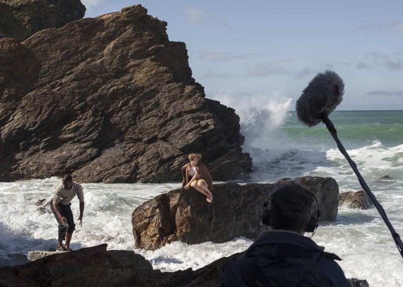 Woman on rock in sea being filmed