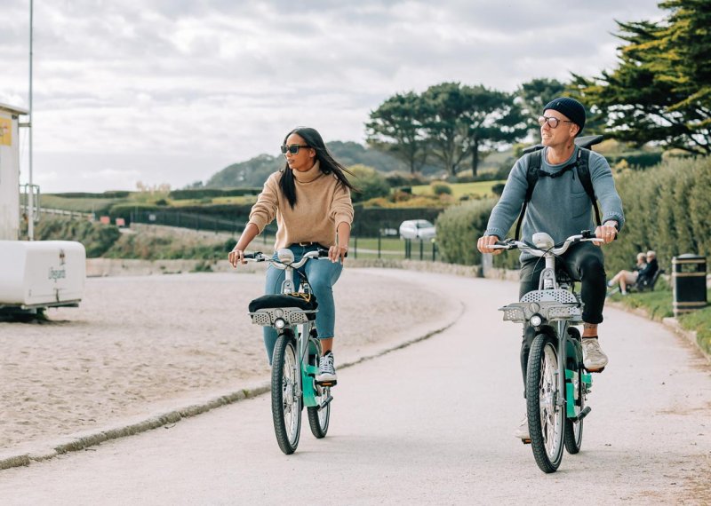 A young man and a woman riding bikes along the beach