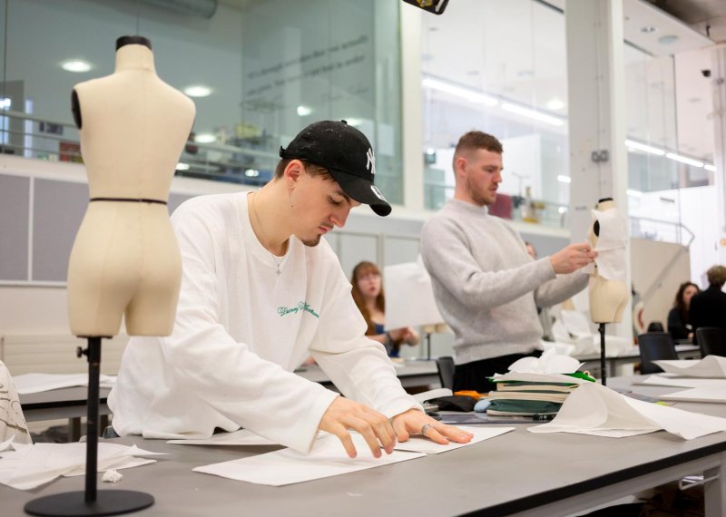 Two Fashion Design students working in a studio with a child's mannequin