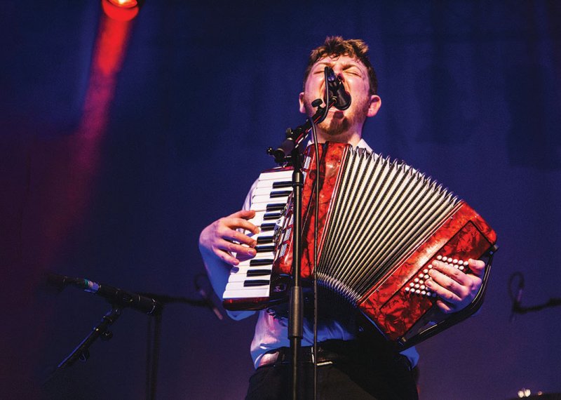 Student singing into microphone and playing accordion