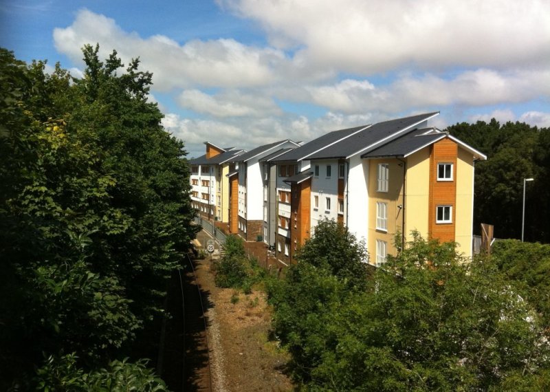A building opposite train tracks and surrounded by trees