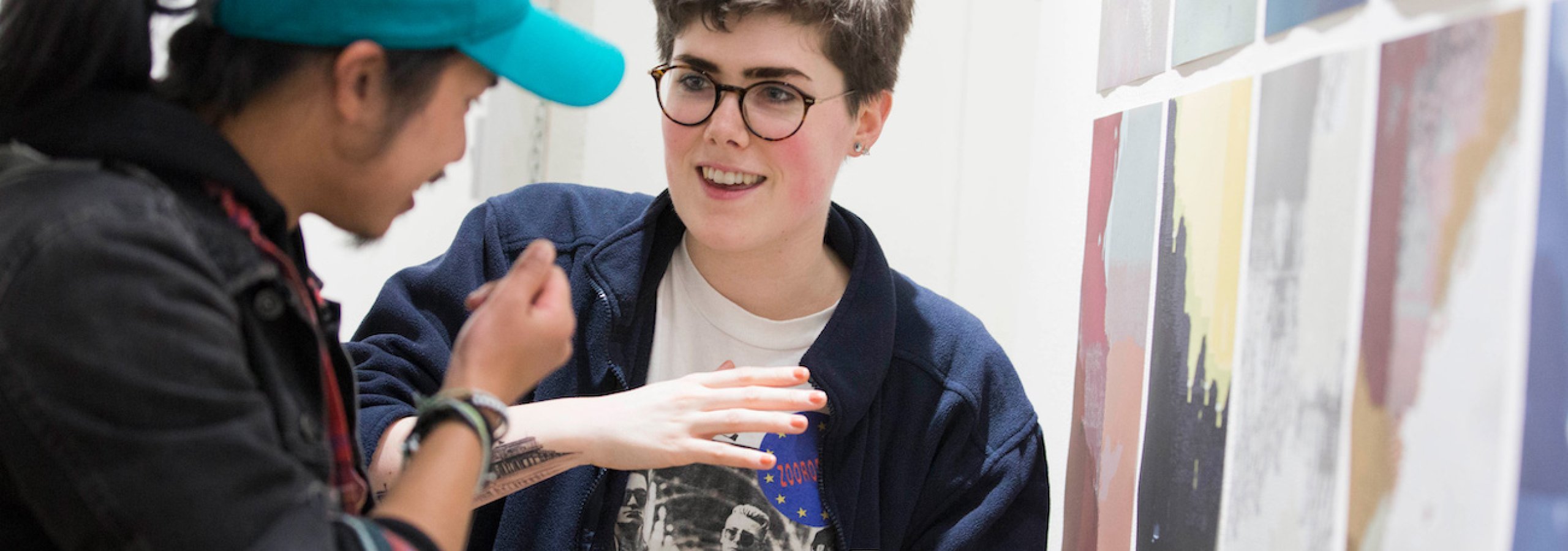 Two Falmouth University students discussing images at an exhibition.