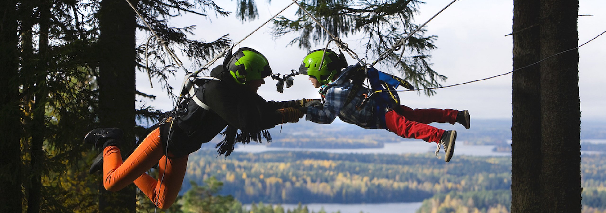 A man and child on a zip wire with trees