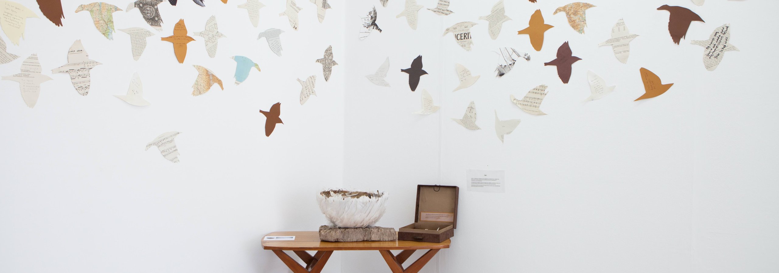 A bowl and small box on a table with cut out birds on the wall