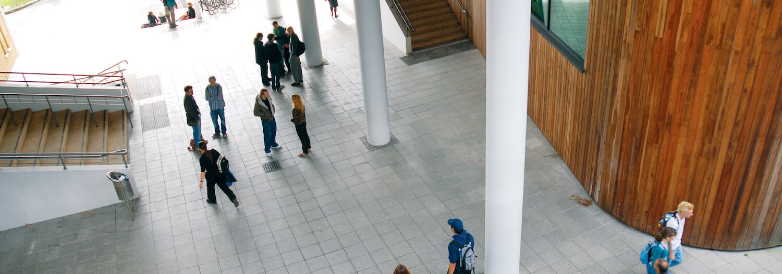 View down onto Penryn campus foyer and people walking and chatting.