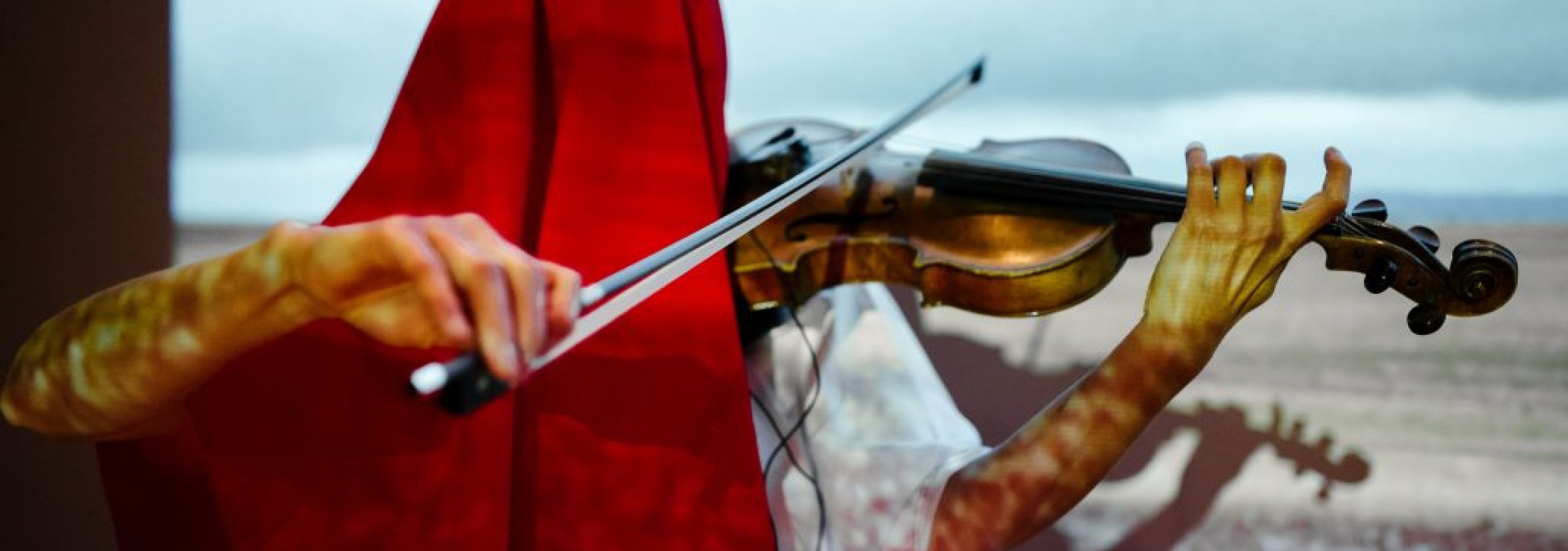 Person under a red shawl playing the violin
