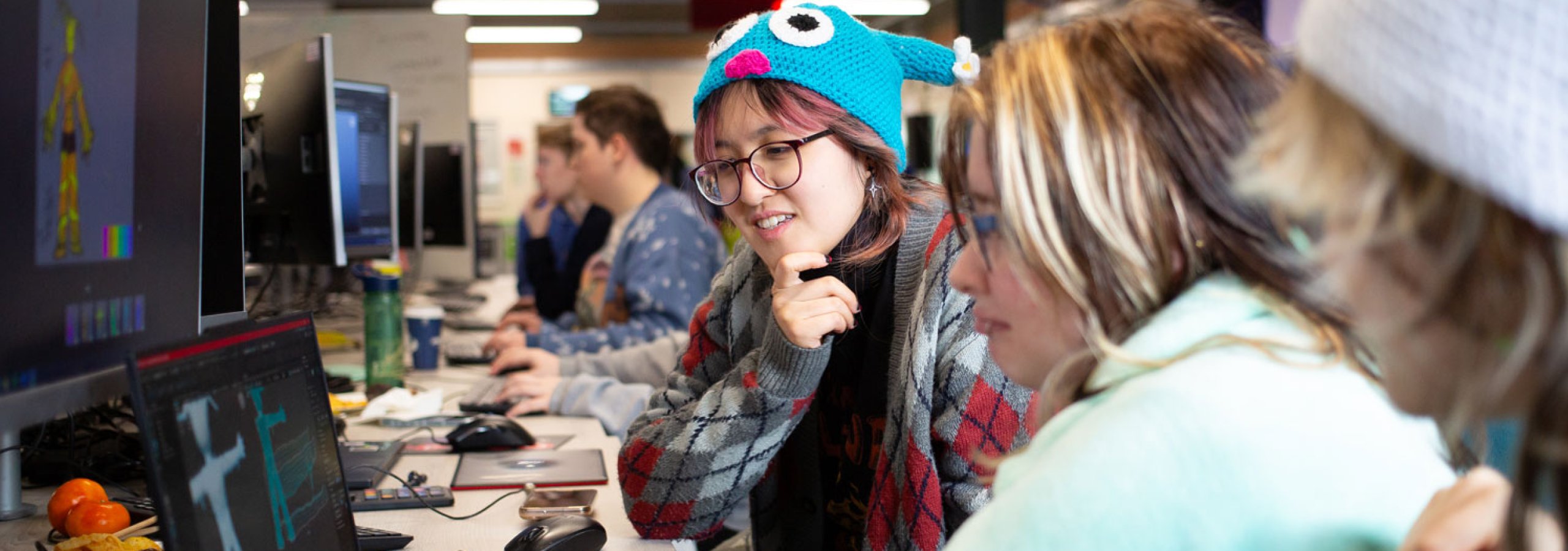 Three Falmouth University students around a computer at the 2025 Games Jam
