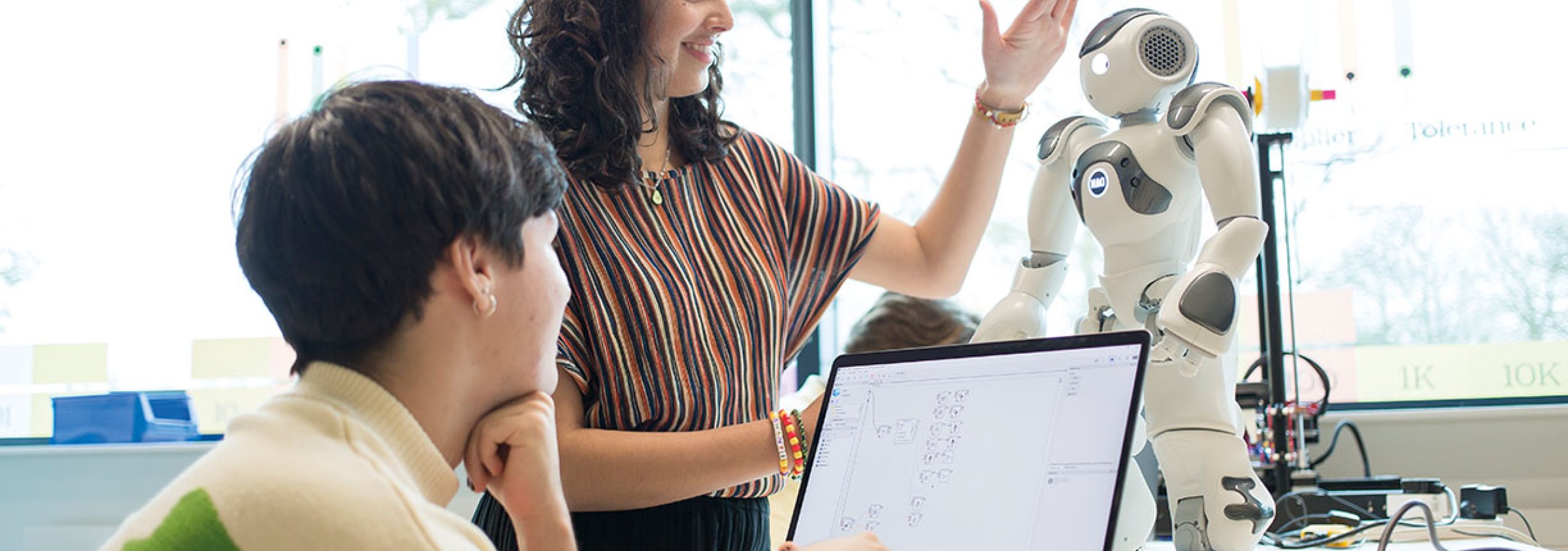 Robotics students discussing with robot on desk