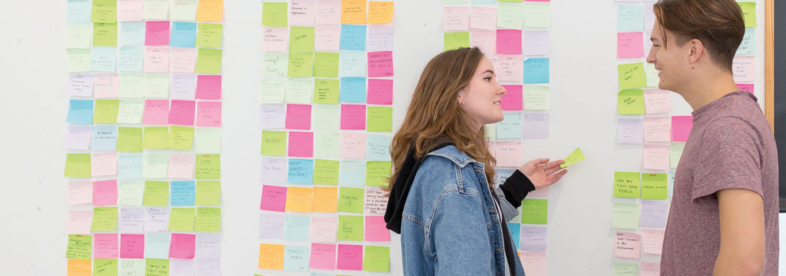 Students stood by a wall of post it notes