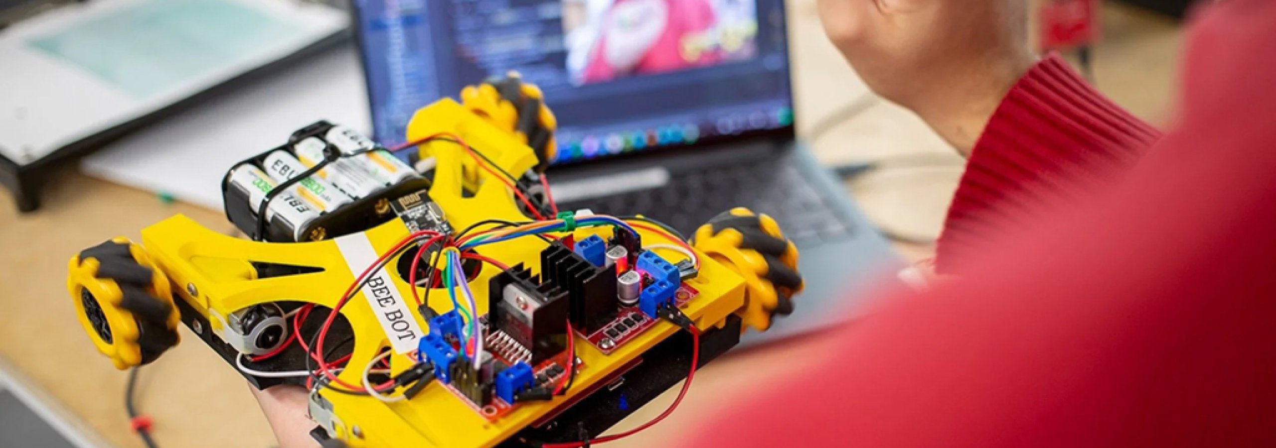 Close up of individual holding a small robotic vehicle