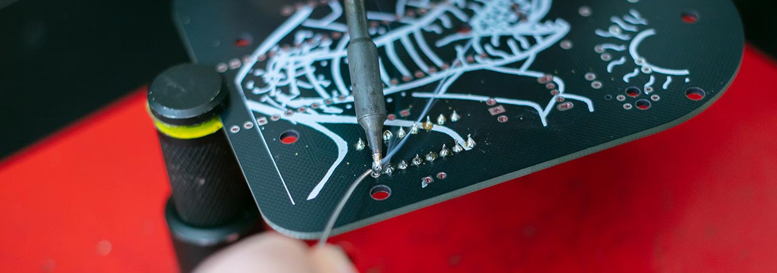 Hands using a soldering iron under a lamp