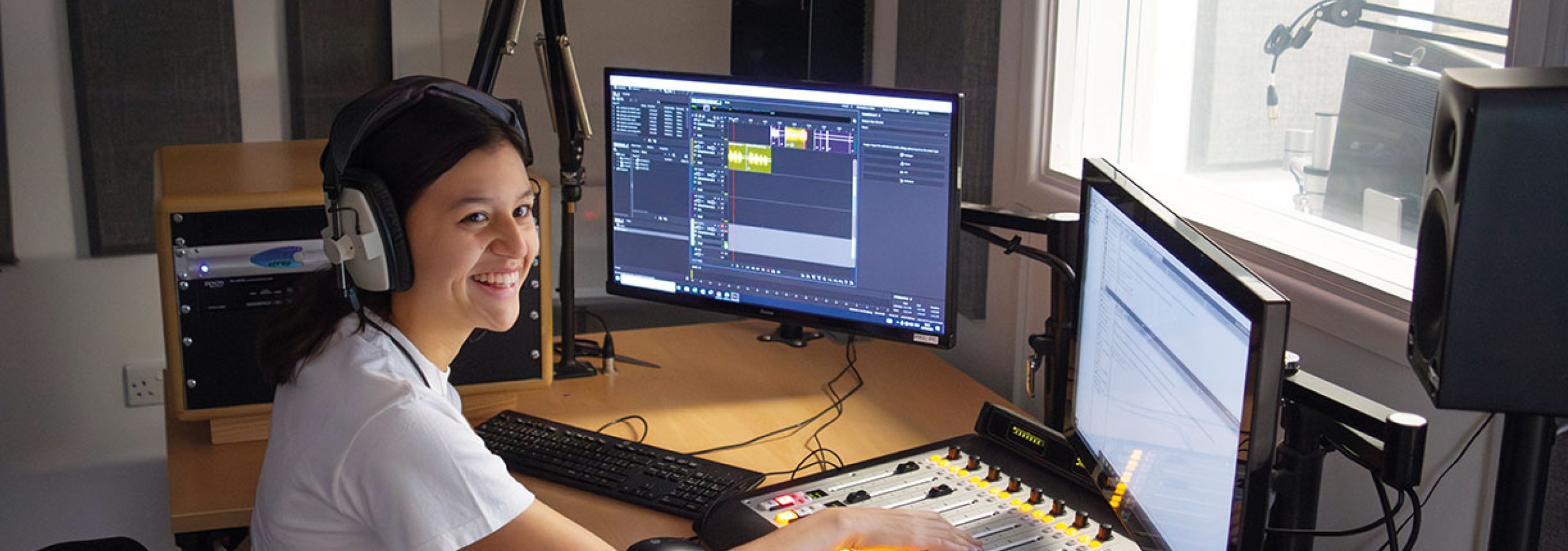 Student working at mixing desk with screens