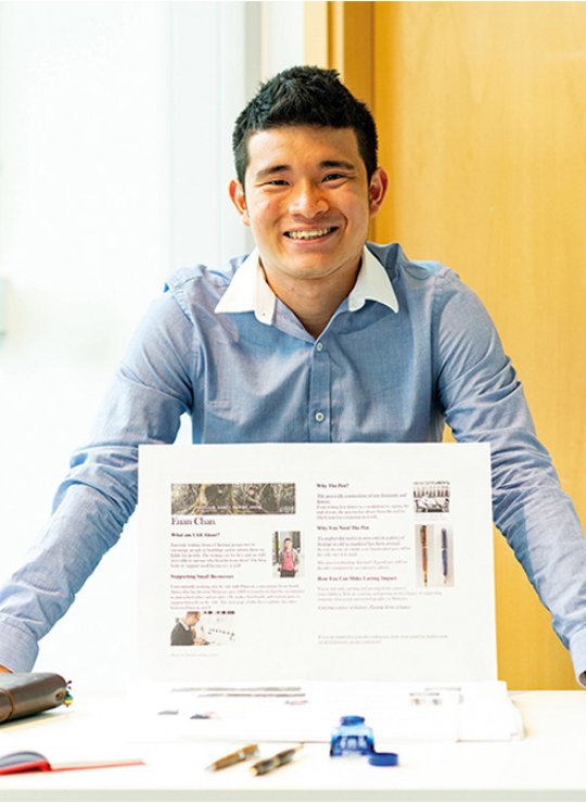 Business & Entrepreneurship student standing at a display table, smiling