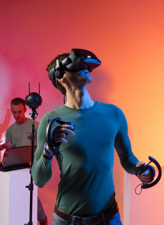 Male student wearing a virtual reality headset with five other students in the background