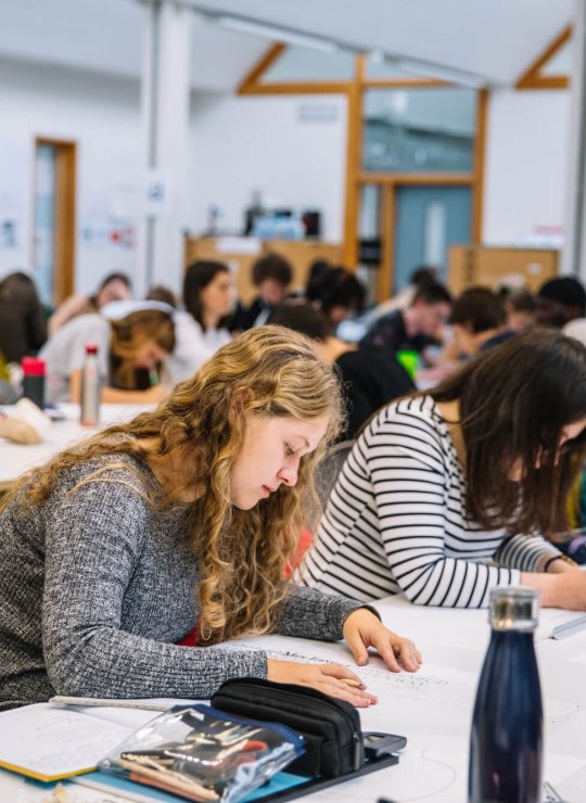 Graphic Design studio full of students busy working at desks at Falmouth University