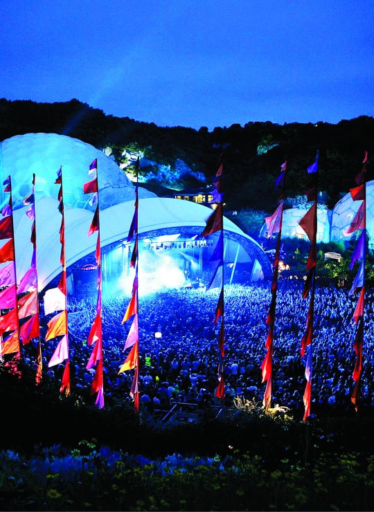A gig at Eden Project at night surrounded by colourful silk flags.