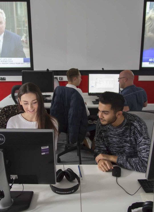 Two Falmouth University Journalism students working together at a computer