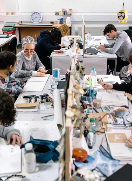 Illustration students in busy studio at desks drawing.